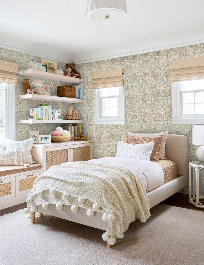 #color::warm | Warm-toned Floral Field Wallpaper by Rylee + Cru is in a child's bedroom with a toy-filled shelf and a bed with a pom pom throw blanket