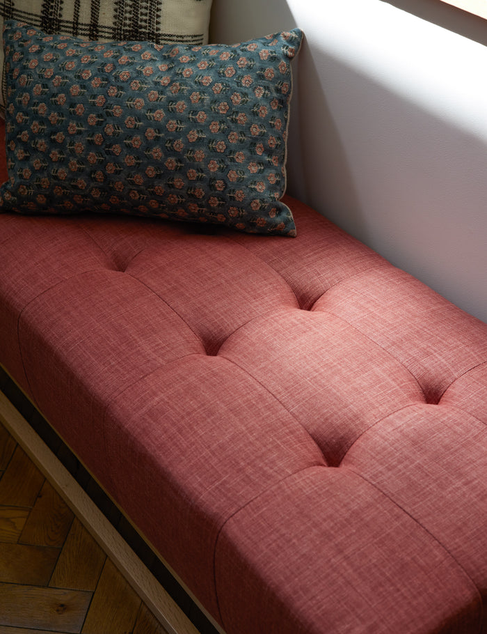 #size::13--x-20- | The Tamra blue and pink lumbar pillow with floral patterns sits on a red linen bench