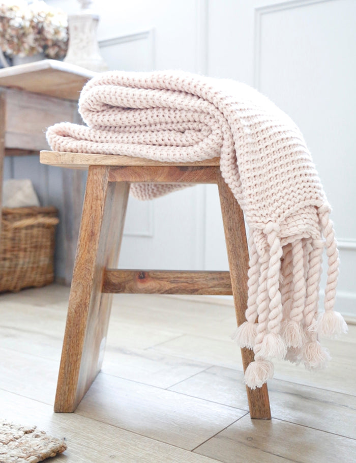 #color::blush | The Trestles blush pink chunky knit throw by pom pom at home lays in a bathroom atop a wooden stool